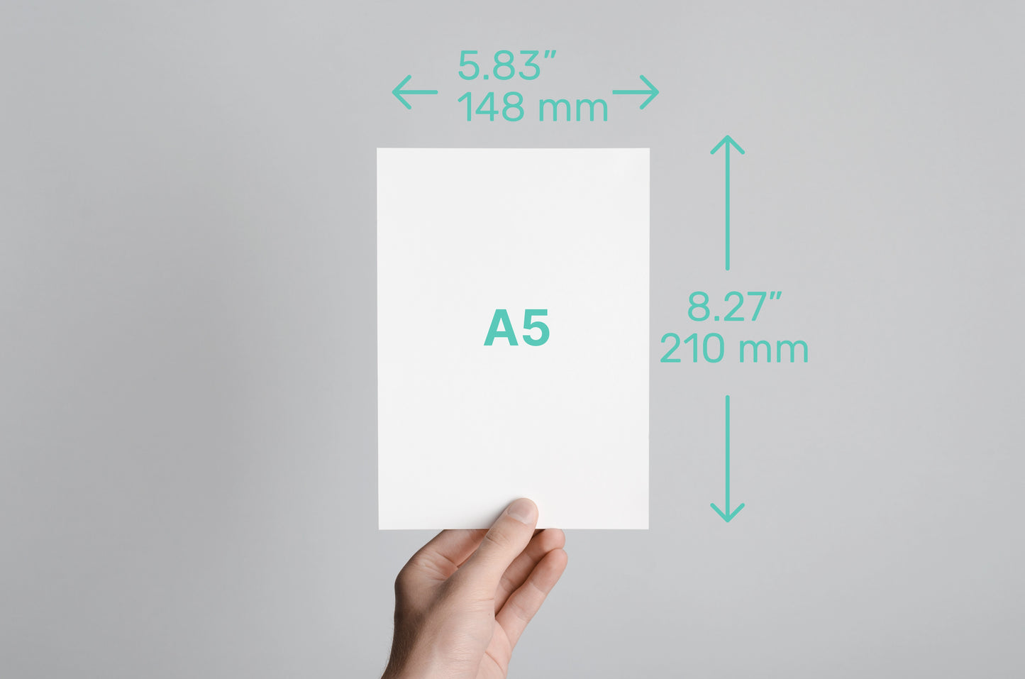 Hand holding a A5 size paper with dimensions labeled on a gray background