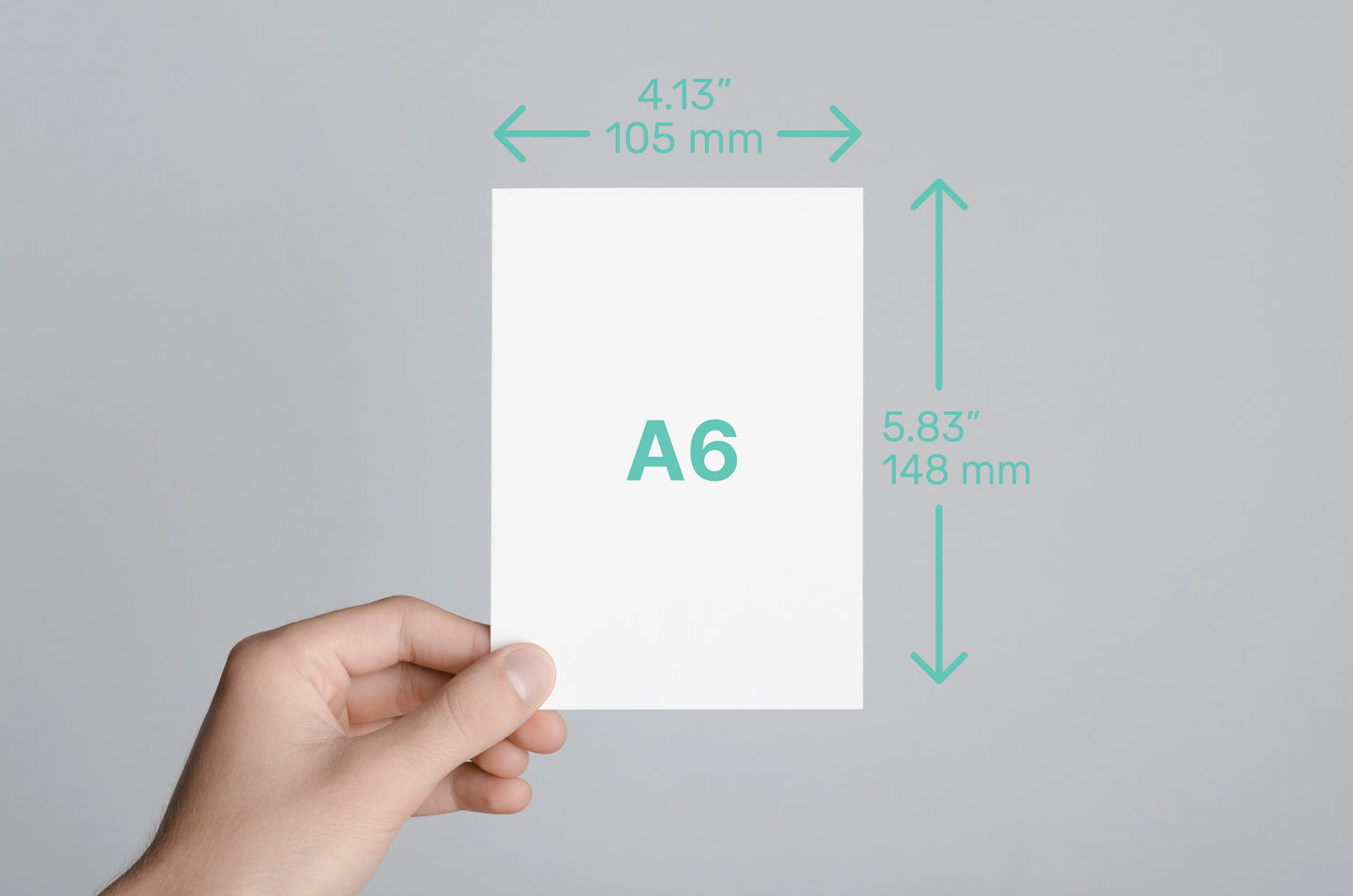Hand holding a piece of paper labeled A6 with dimensions on a gray background